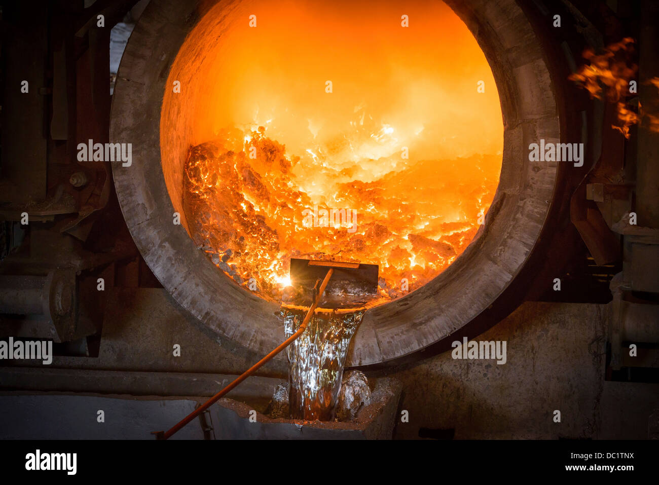 Raking liquid aluminum from furnace at recycling plant Stock Photo