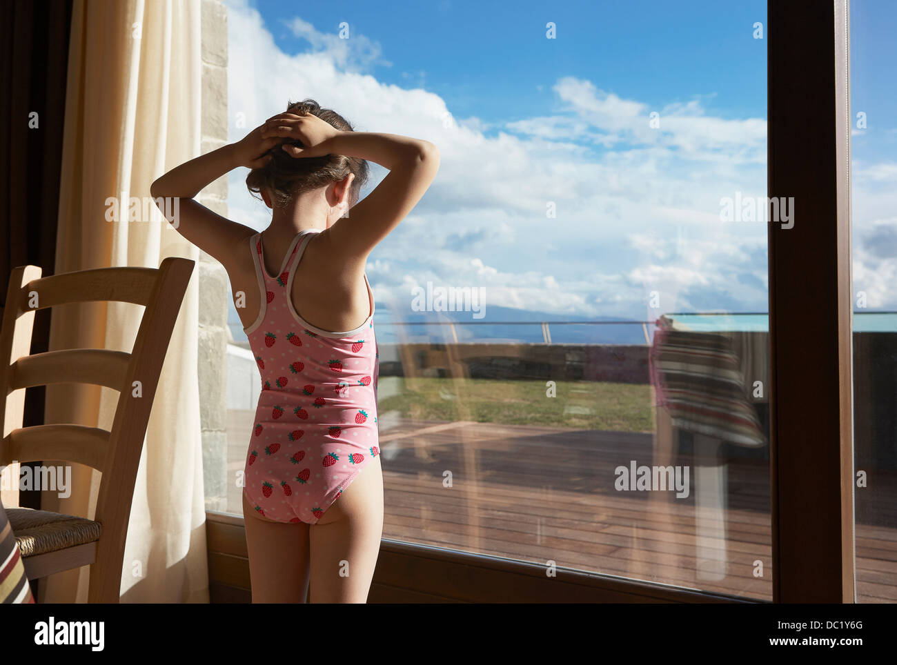 Young girl wearing bathing costume looking out of window Stock Photo