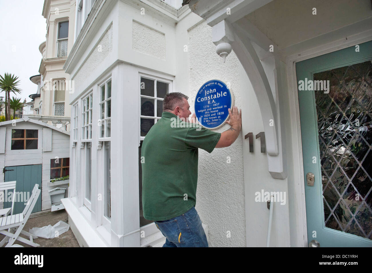 A Heritage Plaque installer fixes a Blue Plaque to the side of a house where John Constable lived in Brighton. Stock Photo