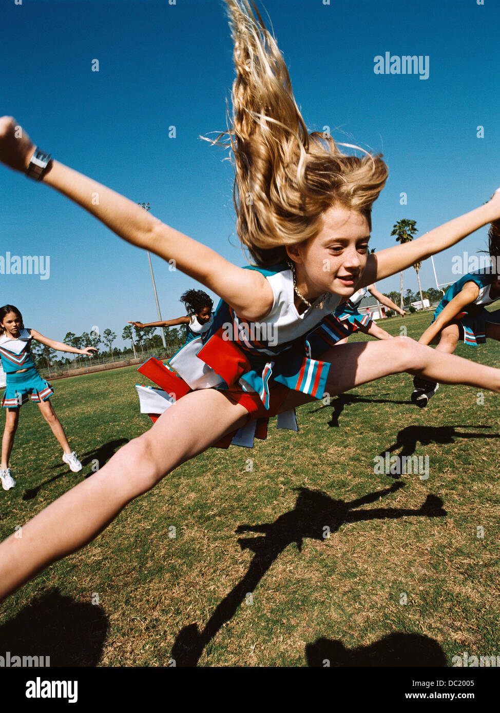 Young cheerleaders performing routine on football field Stock Photo