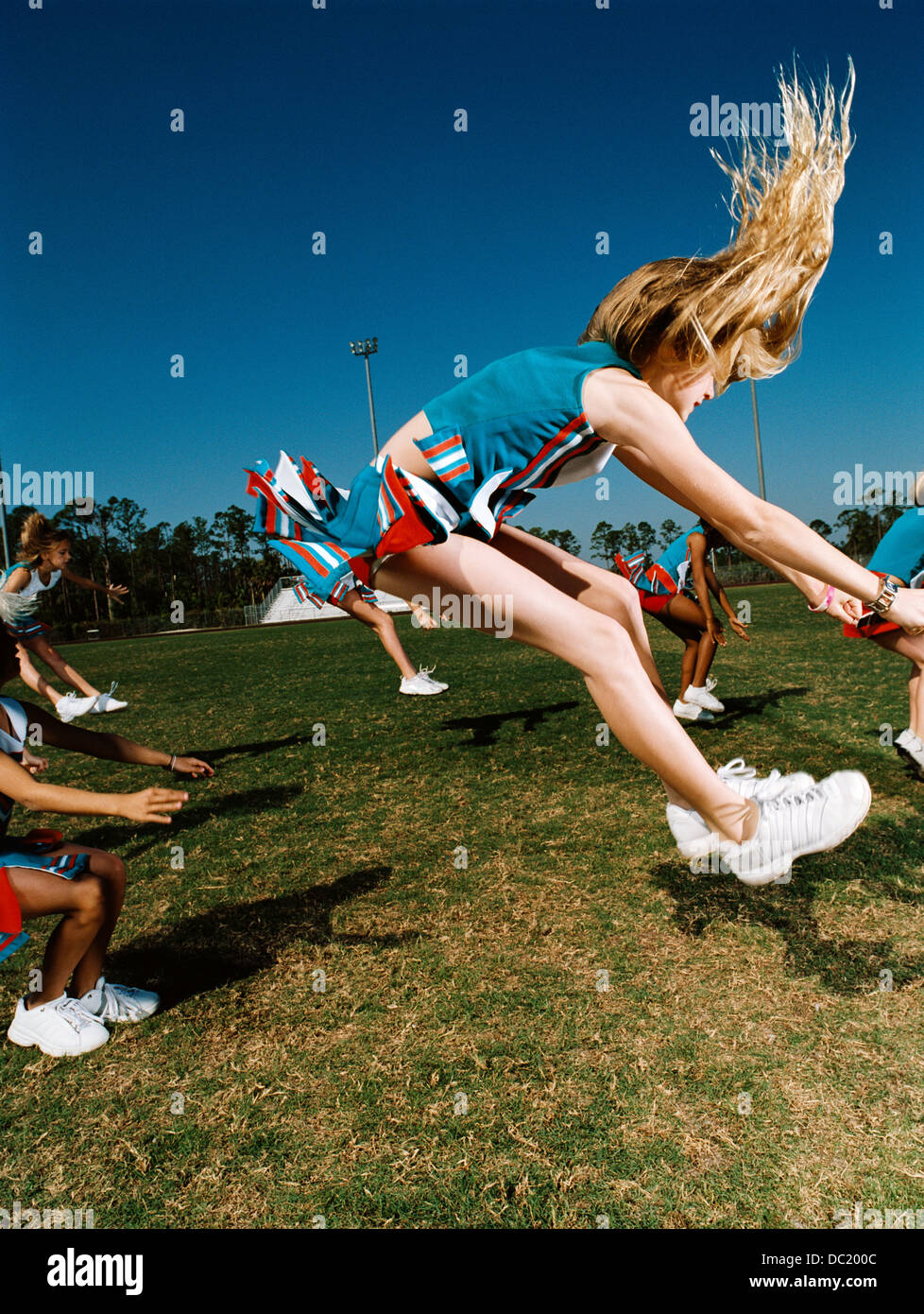 Young cheerleaders performing routine on football field Stock Photo