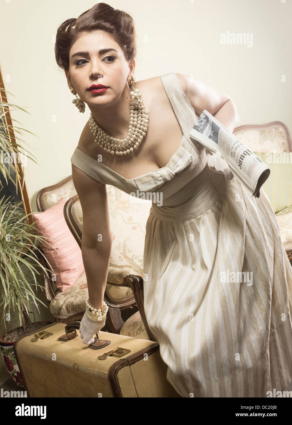 Woman in vintage clothes picking up suitcase Stock Photo