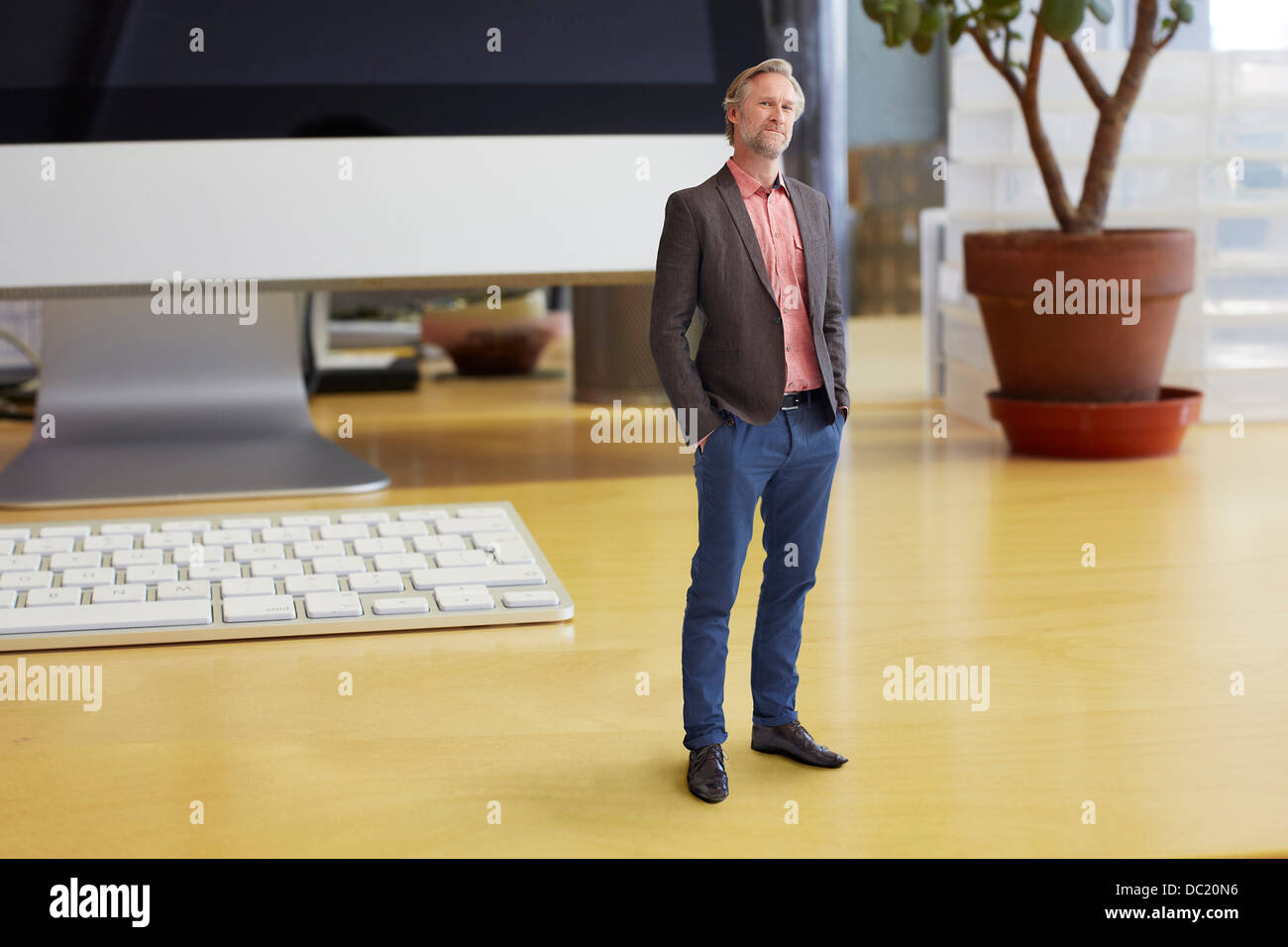 Mature businessman standing on oversized desk Stock Photo