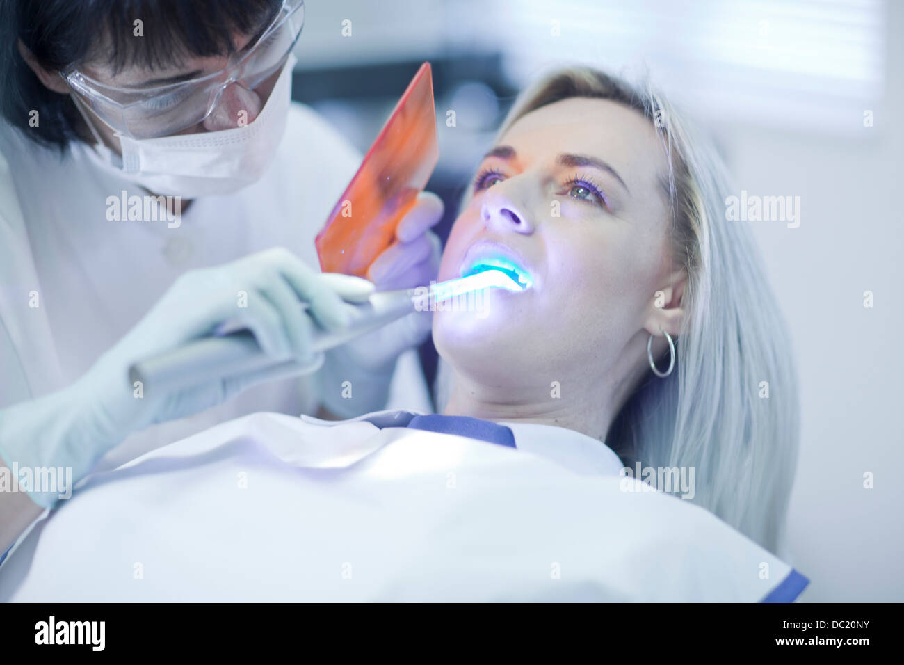 Female dentist using ultraviolet light on patients teeth Stock Photo