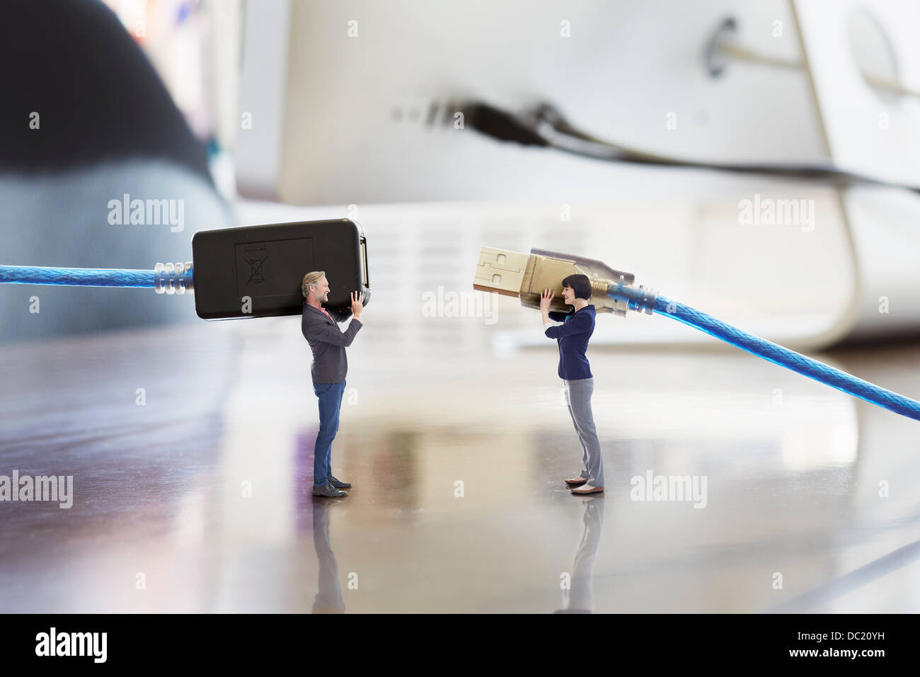 Office colleagues holding large computer cables on oversized desk Stock Photo