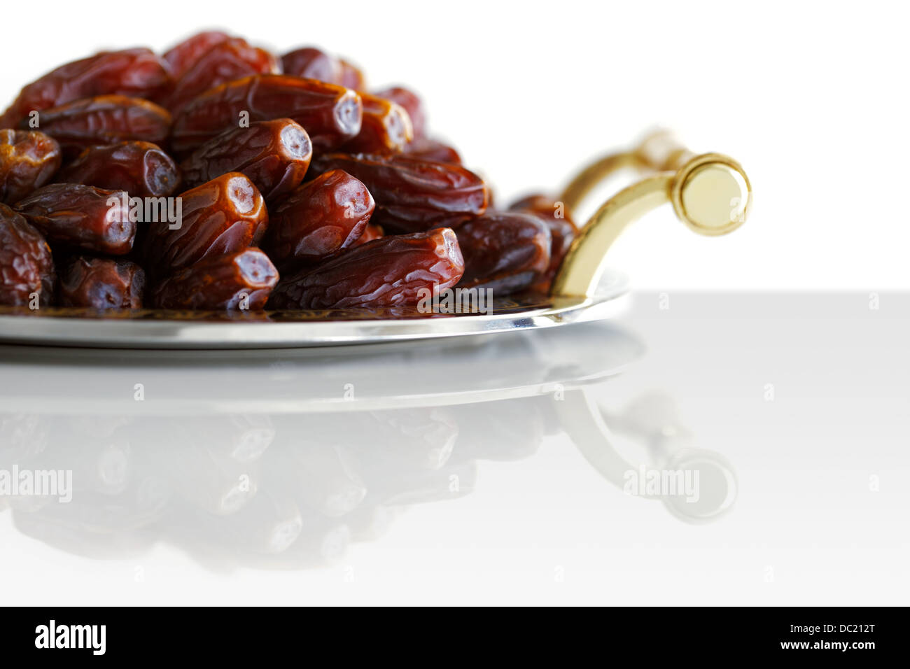 Dried Arabic dates presented on an ornate tray and shot against a white background Stock Photo