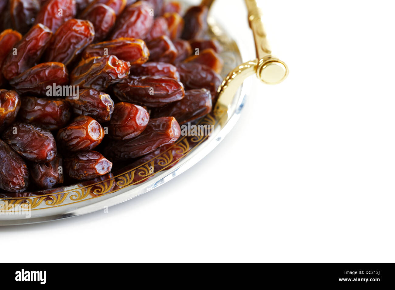 Dried Arabic dates presented on an ornate tray and shot against a white background Stock Photo