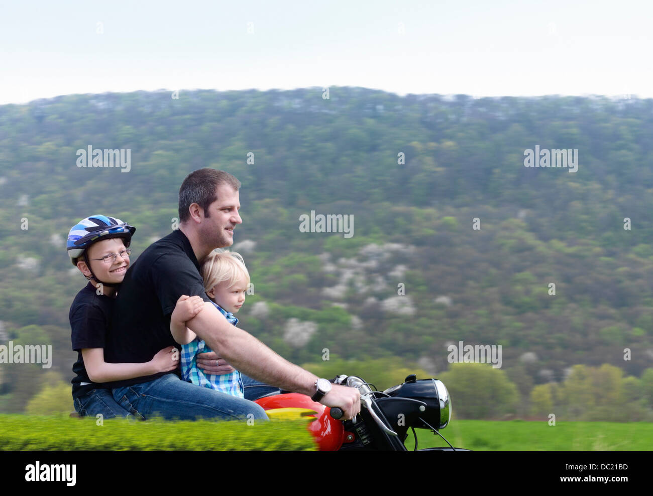 Mature man riding motorbike with sons Stock Photo