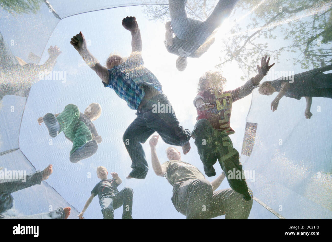 Mature men and boys jumping on trampoline, low angle view Stock Photo