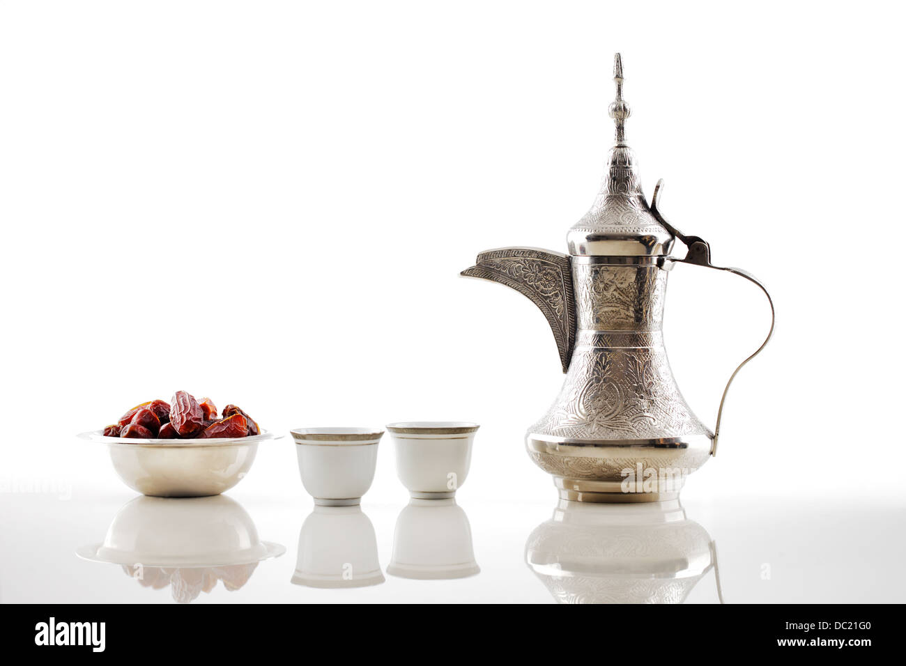 A dallah, a metal pot for making Arabic coffee with a bowl of dried dates Stock Photo