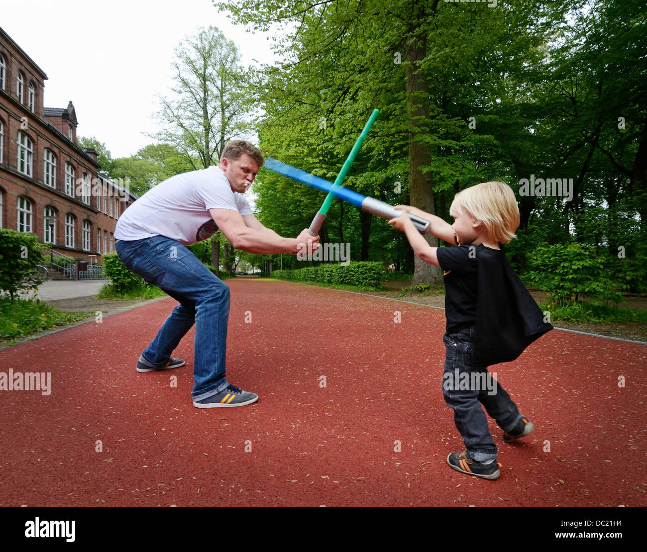 Father and son play fighting with toy swords Stock Photo