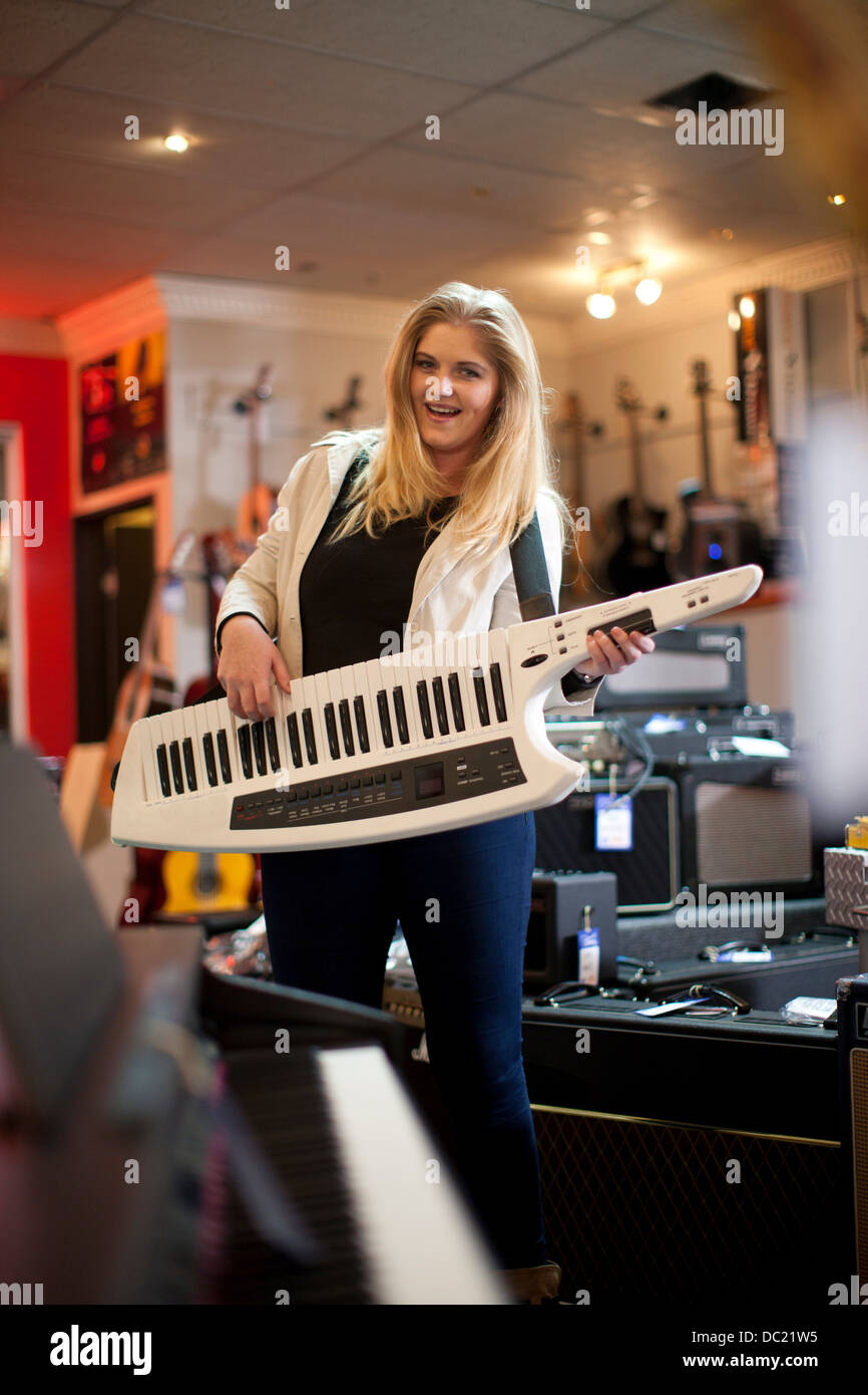 Young woman playing keytar in music store Stock Photo