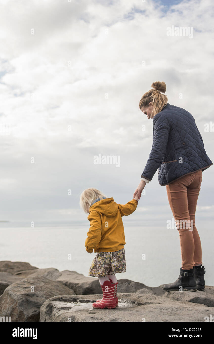 Mother and toddler walking on harbor wall Stock Photo