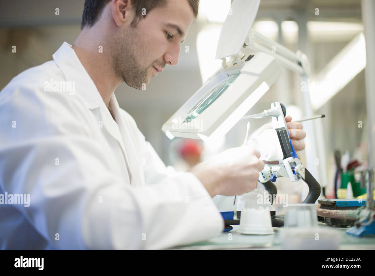Dental technician using magnifier to repair denture Stock Photo Alamy