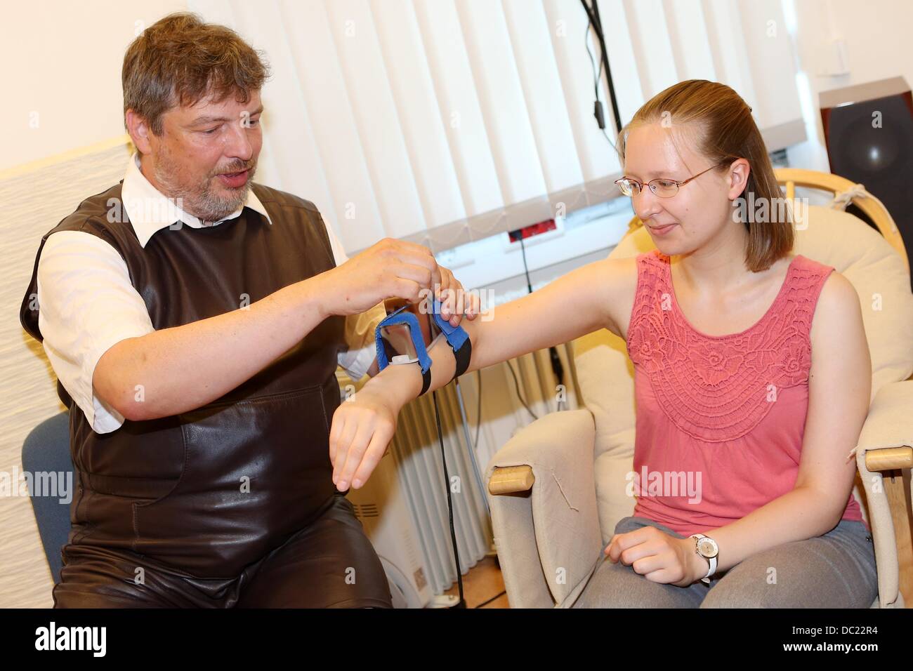 Scientist Christian Kaernbach specialising in the field of goose bumps (horripilation) attaches a goosepimples camera to an arm of a woman at the Leipniz Institute for Science and Mathemaics Education of the University of Kiel, Germany, 23 July 2013. Kaernbach researches on reactions of skin to emotional stimulation with his self-developed camera. Photo: Malte Christians Stock Photo