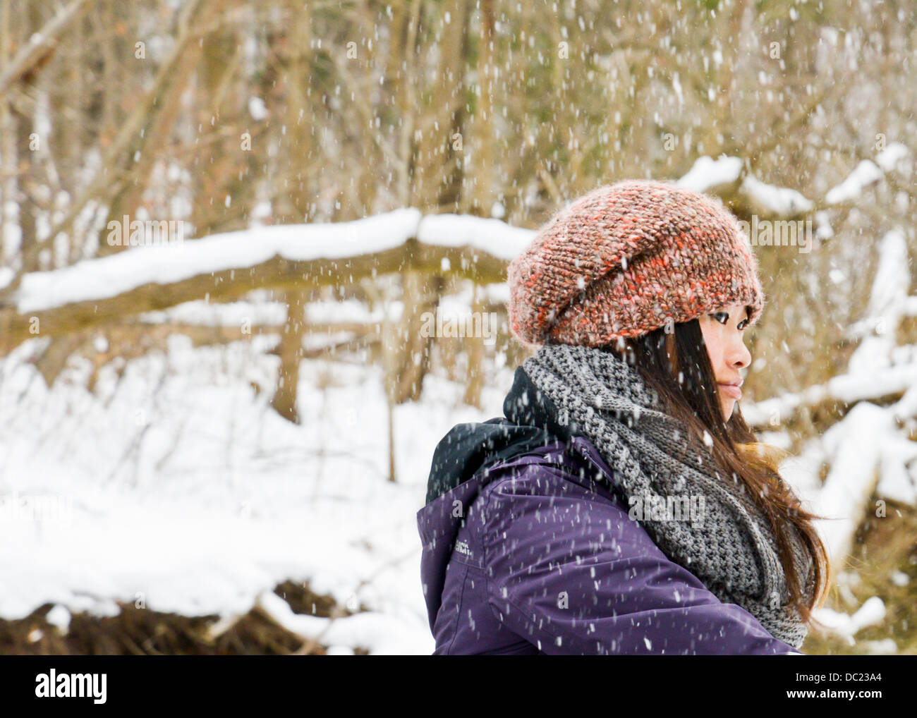 Young woman wearing knit hat and scarf in snow Stock Photo