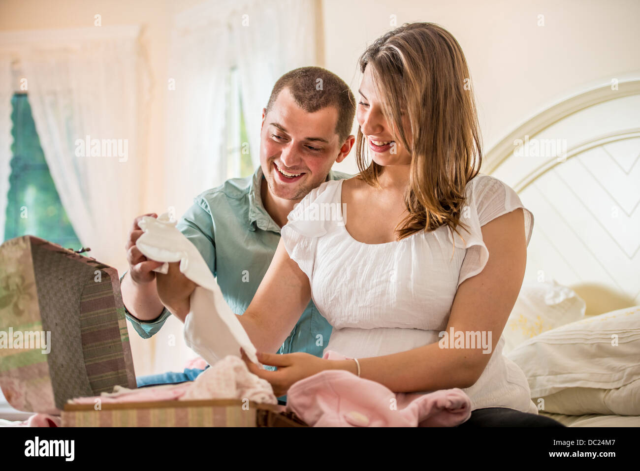 Couple looking through case of baby clothes Stock Photo