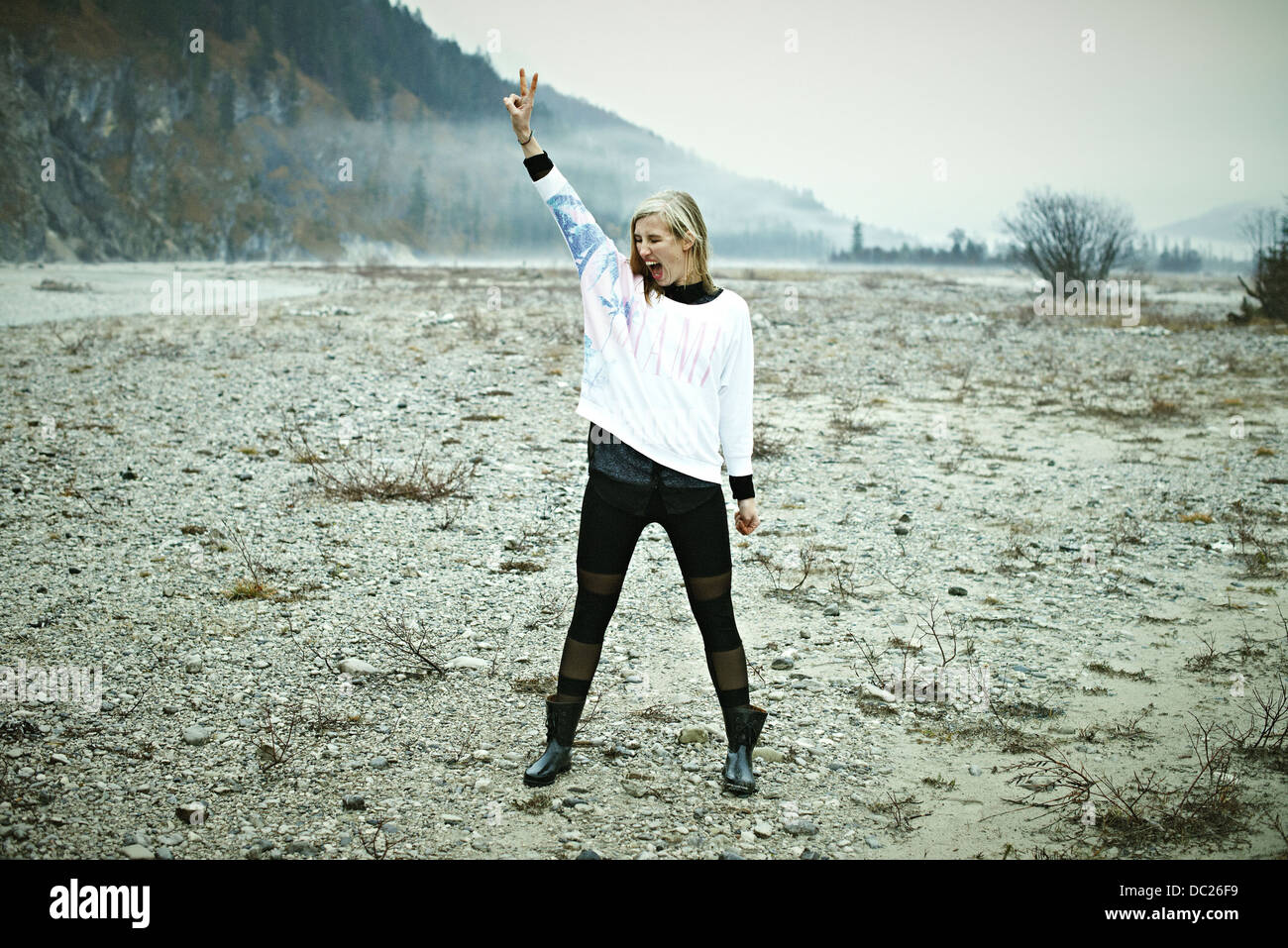 Woman standing in remote setting making peace sign Stock Photo