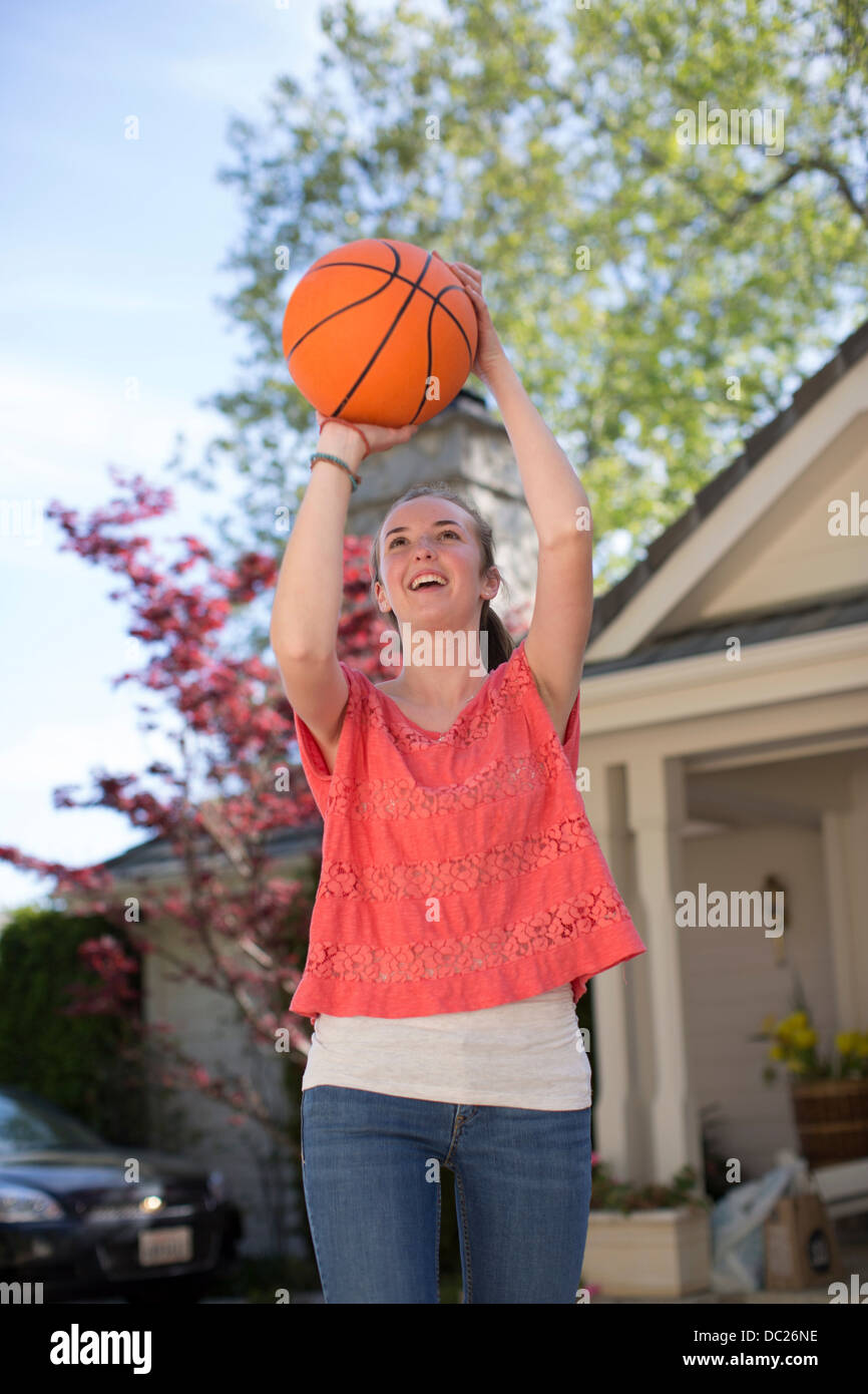 Teenage girl holding basketball above head Stock Photo
