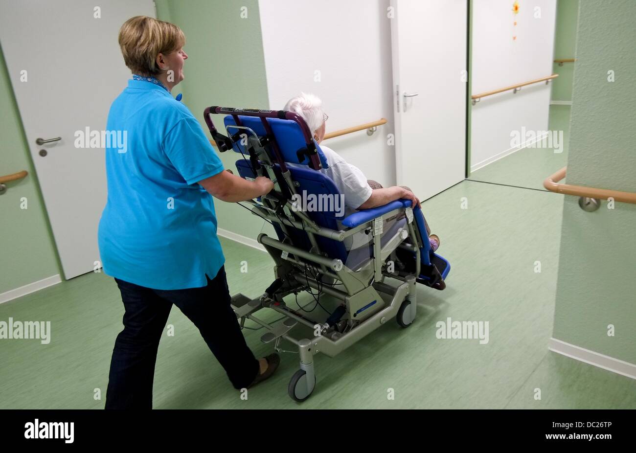 Nurse Anja von Westerhagen pushes resident of the nursing home Heidemarie Mueller-Hein along a hallway of the care home APE with a wheelchair in Hanover, Germany, 11 June 2013. As of recently, the city of Hanover has a nursing home for people who are overweight. Photo: Peter Steffen Stock Photo