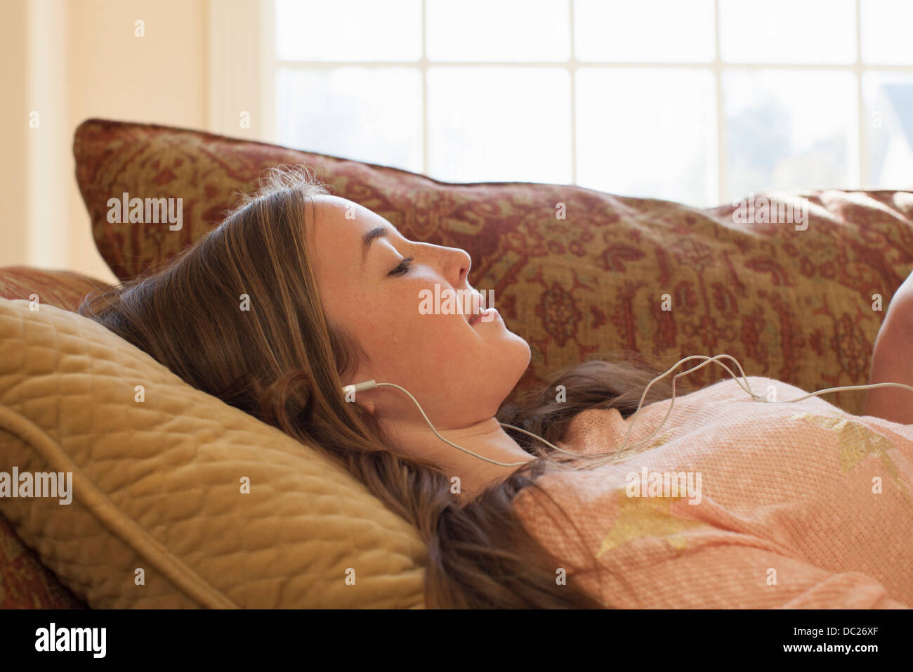 Teenage girl lying on sofa with earphones Stock Photo - Alamy