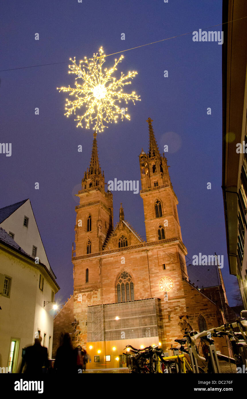 Switzerland, Basel. Historic church at Munsterplatz Winter Holiday Market. Christmas lights on a snowy winter night at plaza. Stock Photo