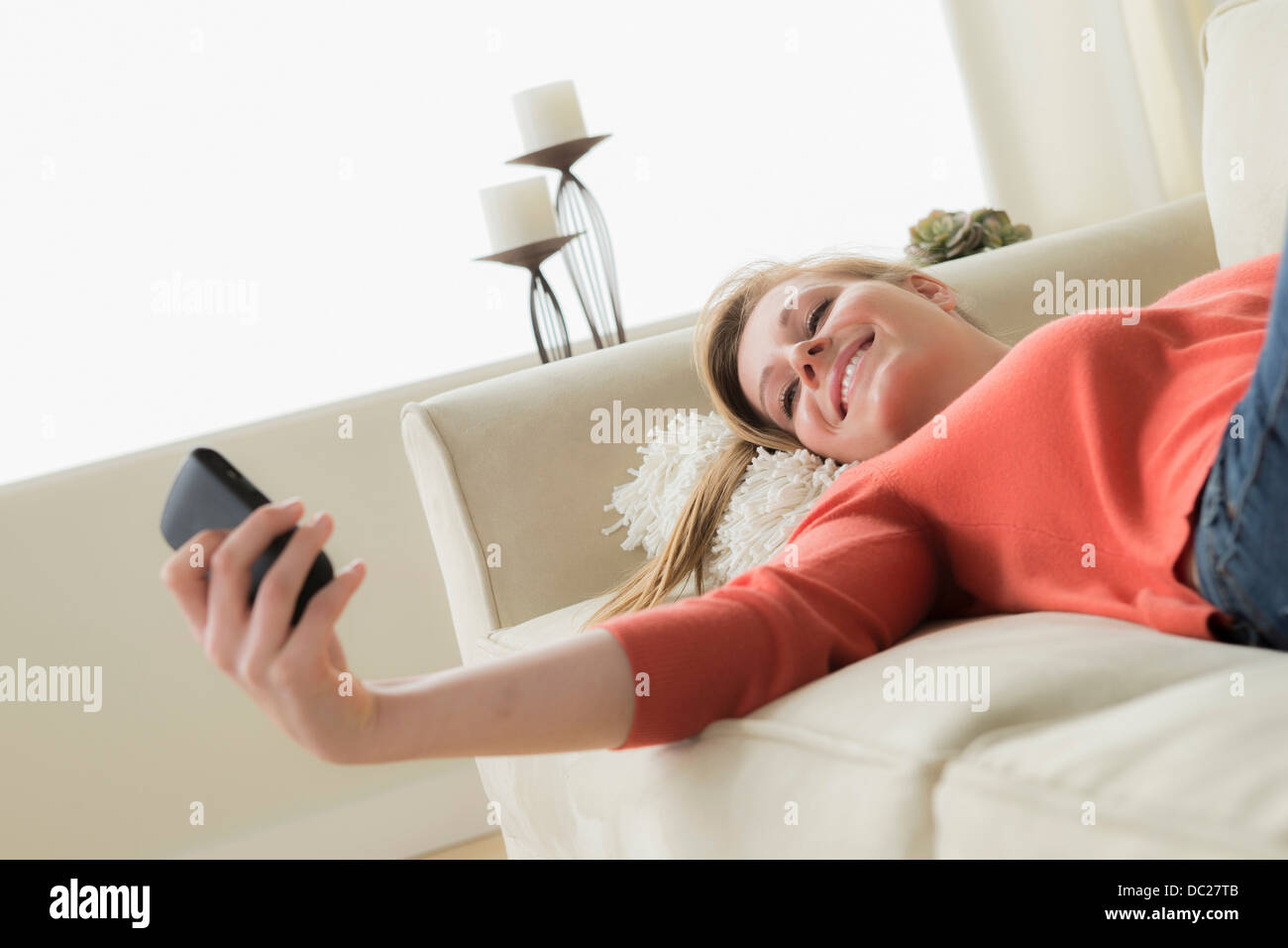 Teenage girl on sofa with cell phone, smiling Stock Photo - Alamy