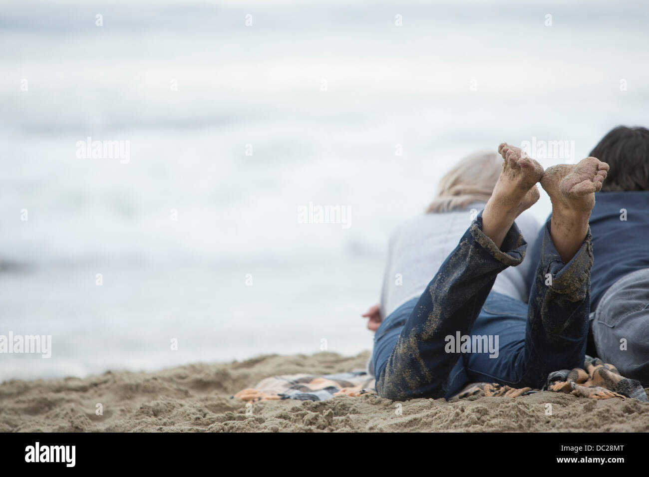 Mature couple lying on beach looking at sea Stock Photo