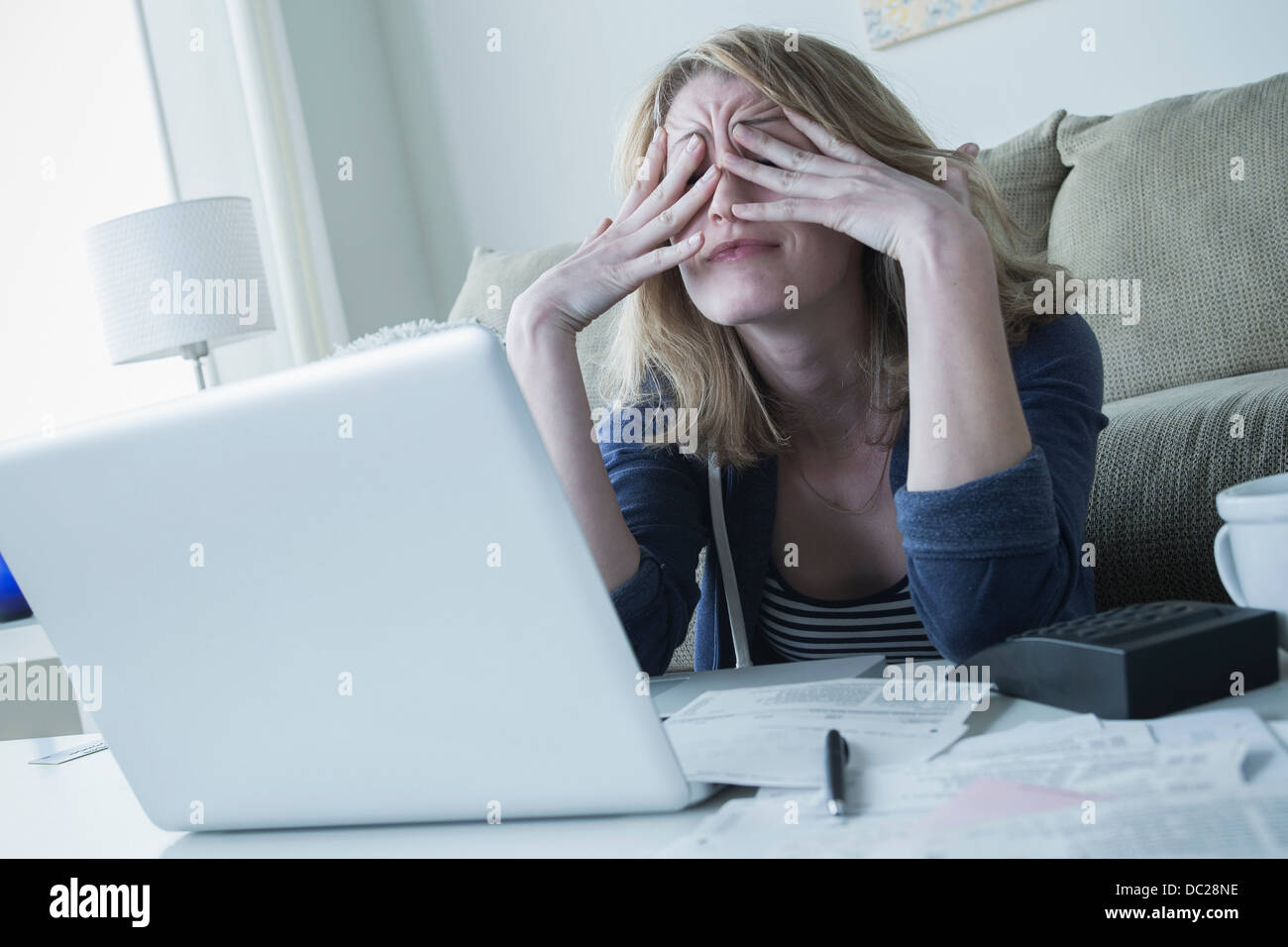 Stressed young woman rubbing eyes Stock Photo