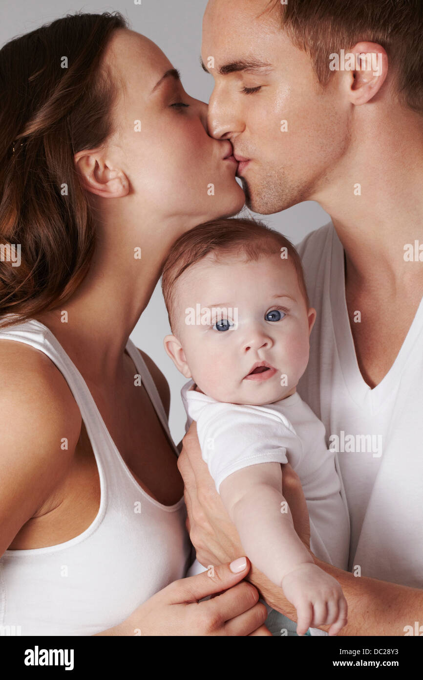 Mother and father kissing, with baby daughter Stock Photo