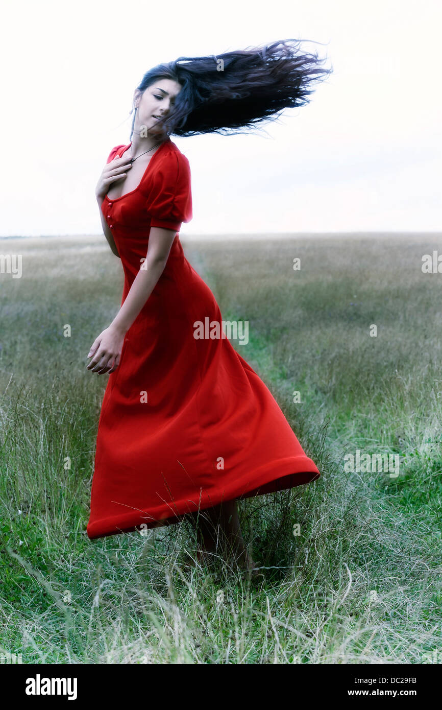 a woman in a red dress is dancing on a field Stock Photo - Alamy