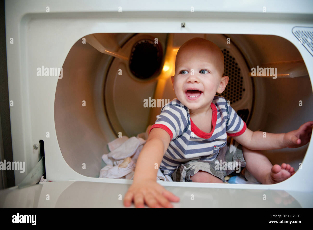 Baby boy sitting in tumble dryer Stock Photo Alamy