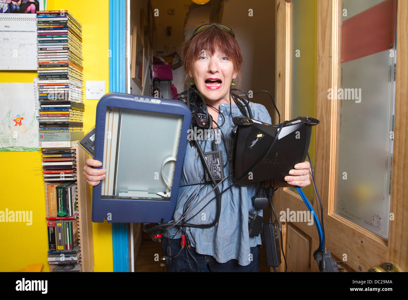 Woman with technophobia struggling with electronic devices at home, London, UK Stock Photo