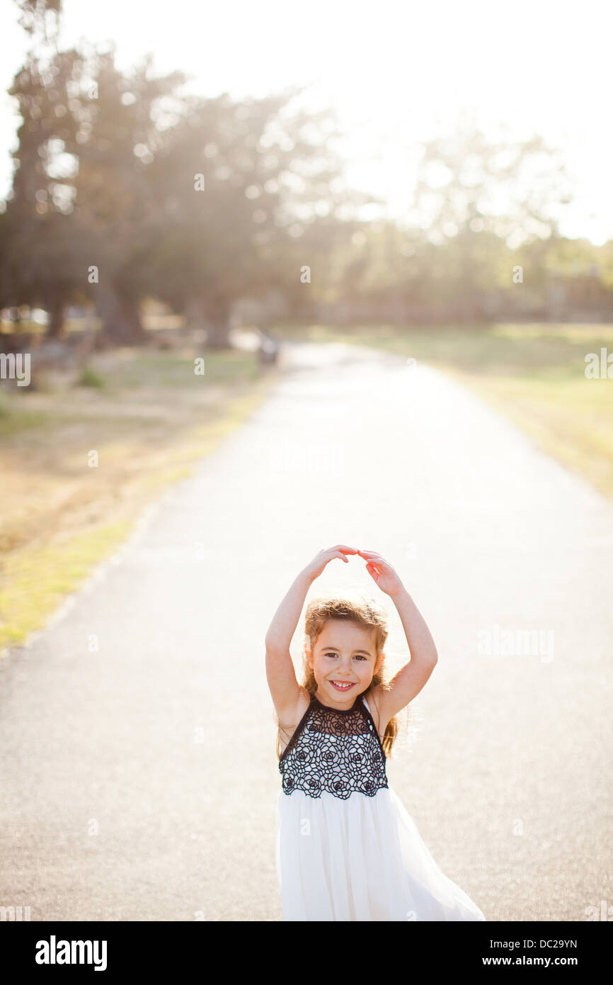 Portrait of girl on lane with arms above head Stock Photo