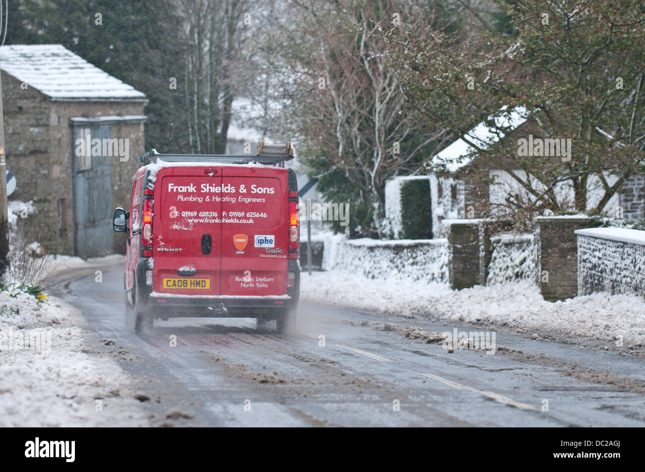 A van Drives through the snow in Askrigg, North Yorkshire, UK Stock Photo