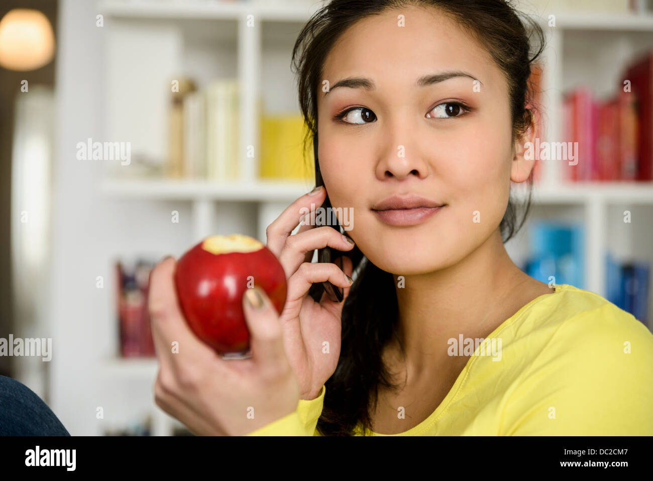 Woman with red apple listening to mobile phone Stock Photo