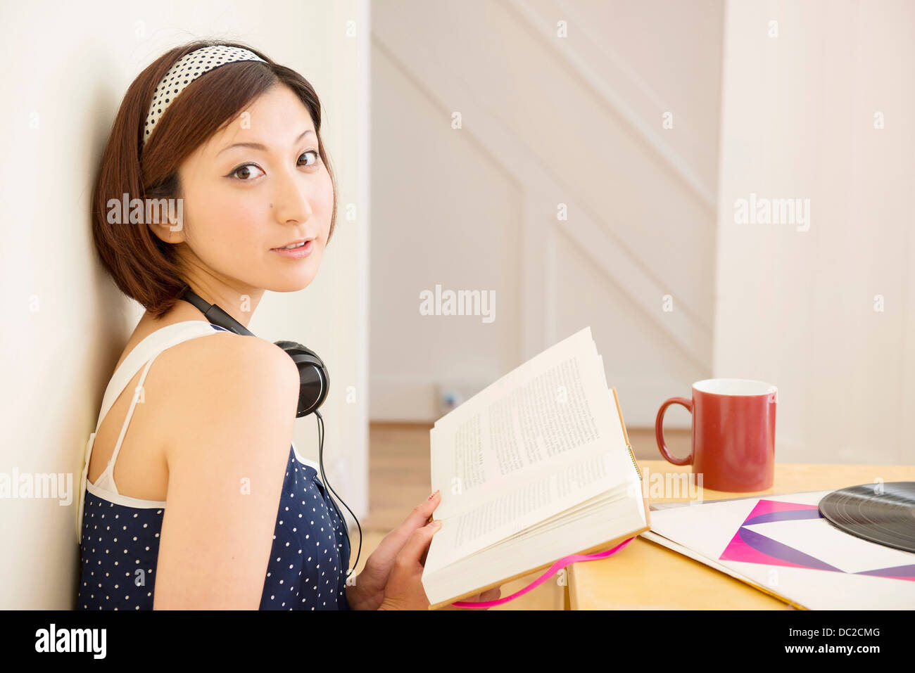 Woman looking up from book Stock Photo