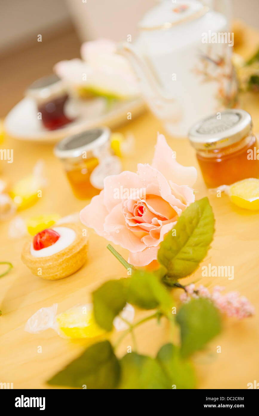 Rose on table with teatime treats and sweets Stock Photo