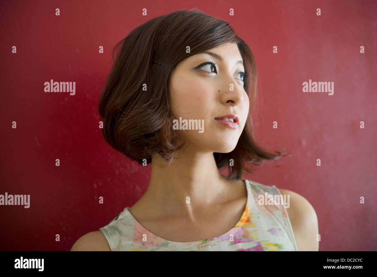Woman against red wall looking into distance Stock Photo