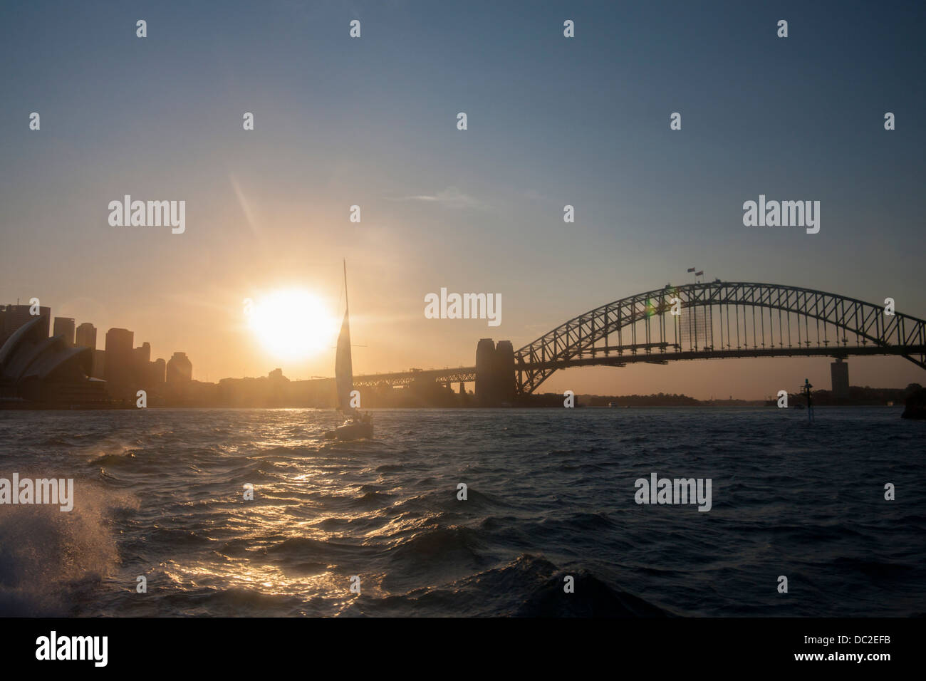 Yacht sailing in Sydney Harbour at sunset with Harbour Bridge in ...