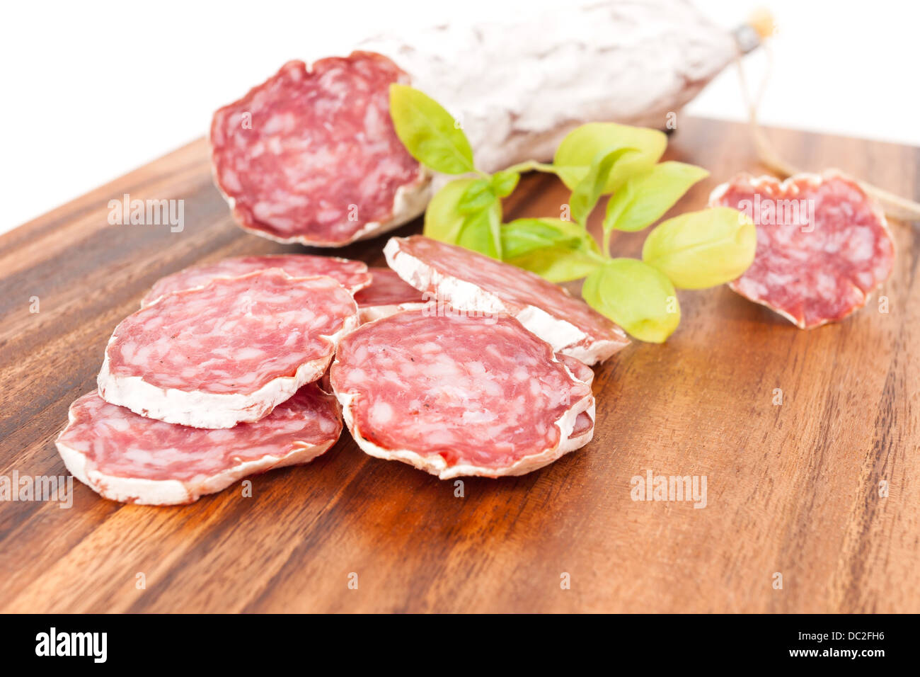 sliced salami on white background with basil leaves Stock Photo - Alamy