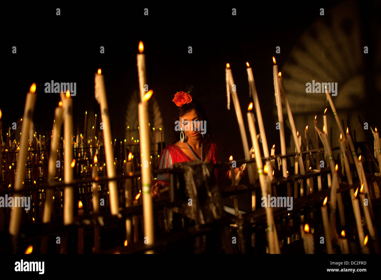 A woman lights a candle in the Votive Room of the shrine of the Virgin of Rocio in Andalusia, Spain. Stock Photo