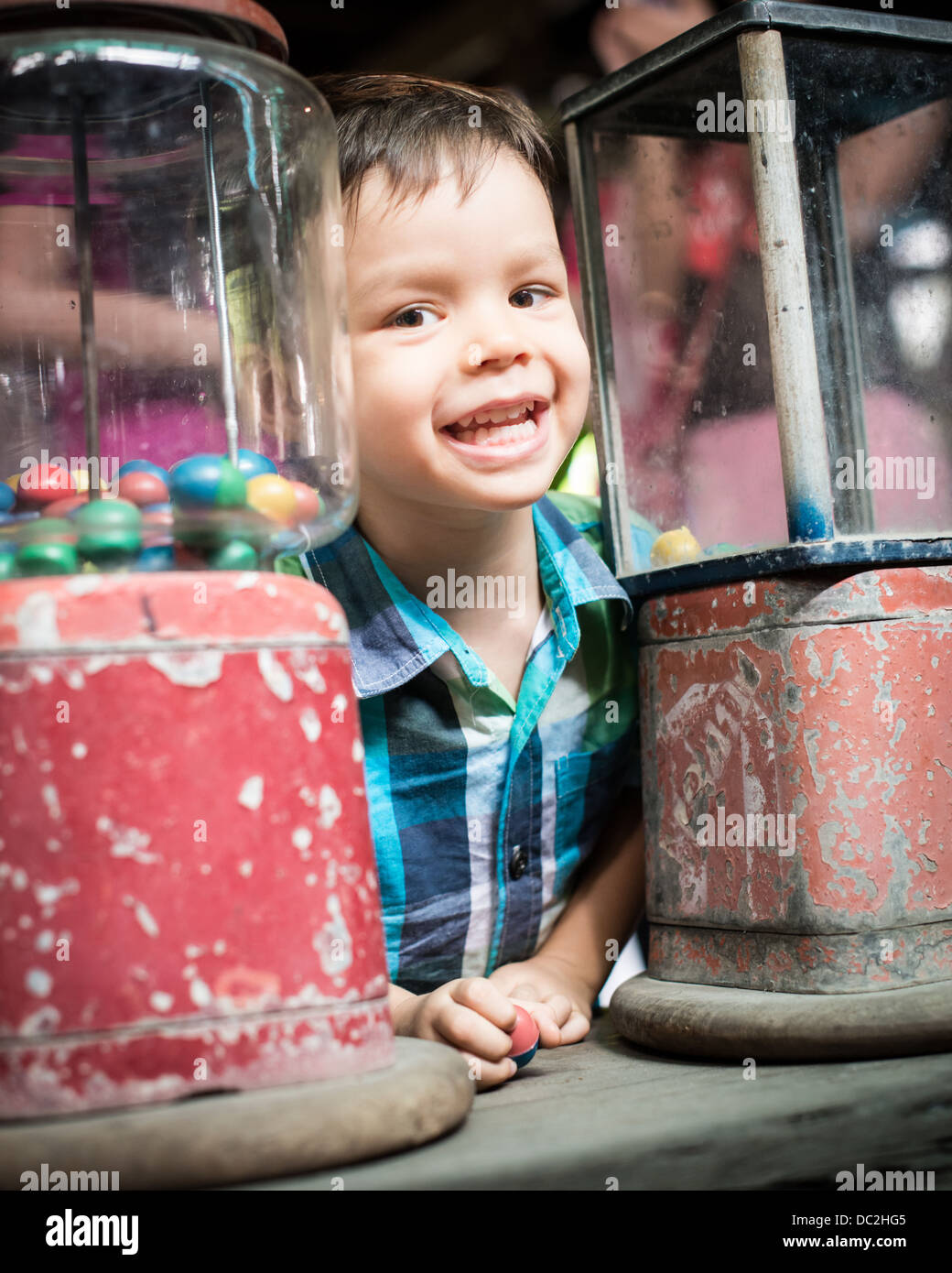 Series of photos of a 2 year old mixed race Asian Caucasian child enthusiastically getting a toy from a vintage vending machine Stock Photo