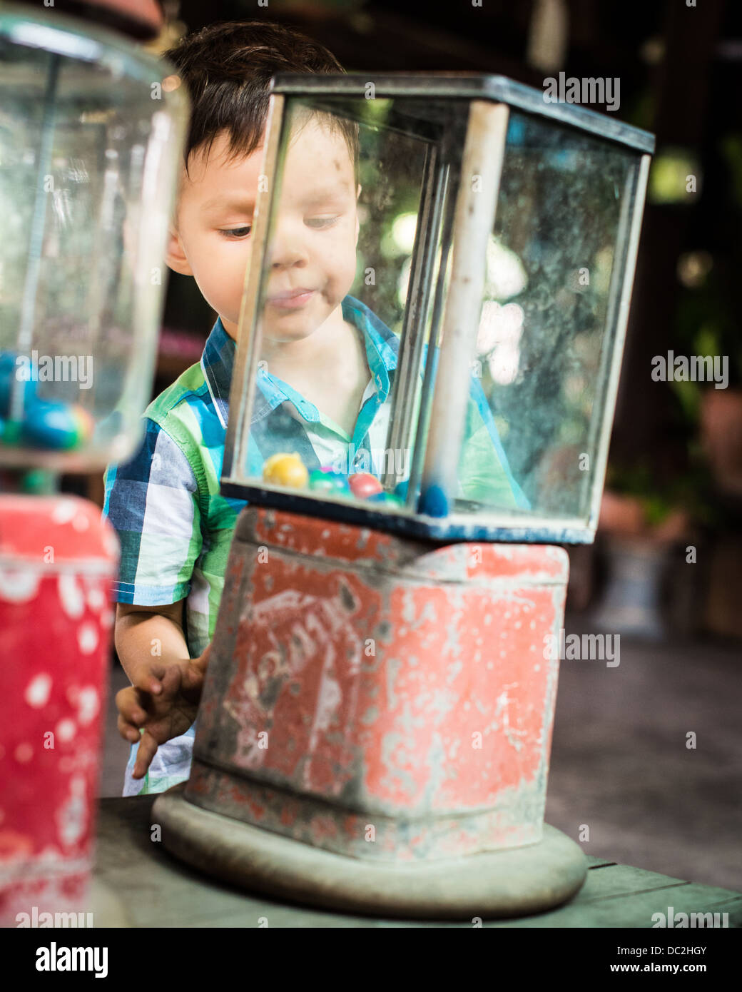 Series of photos of a 2 year old mixed race Asian Caucasian child enthusiastically getting a toy from a vintage vending machine Stock Photo