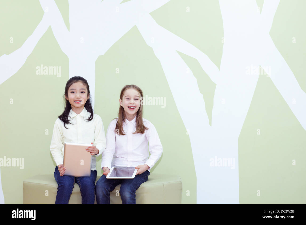 two girls sitting on a chair with tablet PC Stock Photo - Alamy