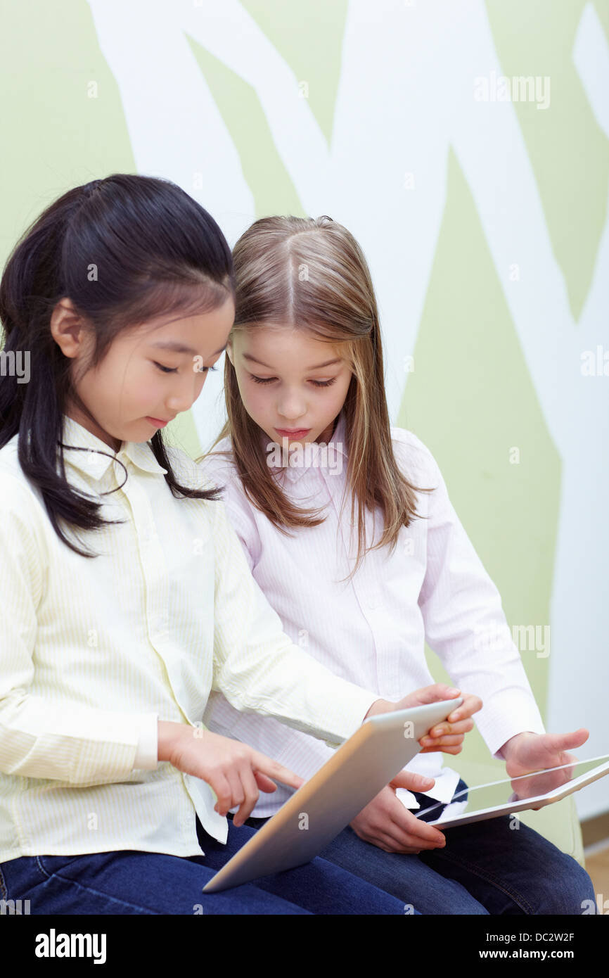 two girls sitting on a chair with tablet PC Stock Photo - Alamy