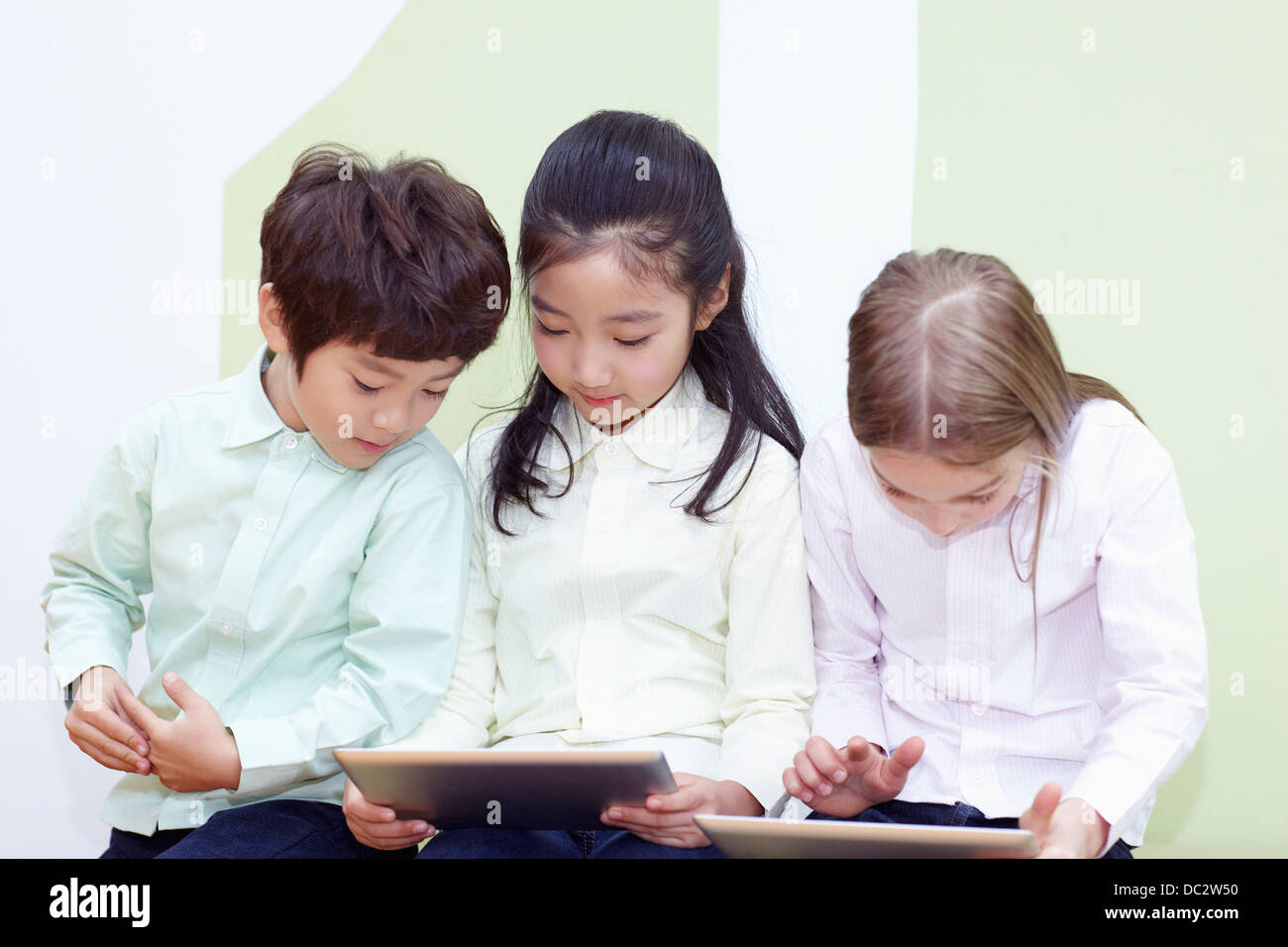 kids sitting playing with tablet PCs Stock Photo