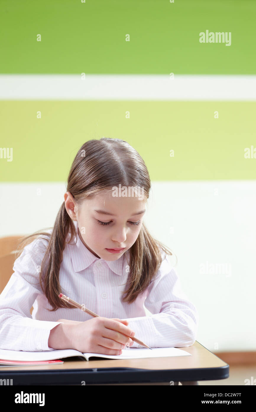 a girl sitting at a desk in a classroom studying Stock Photo - Alamy