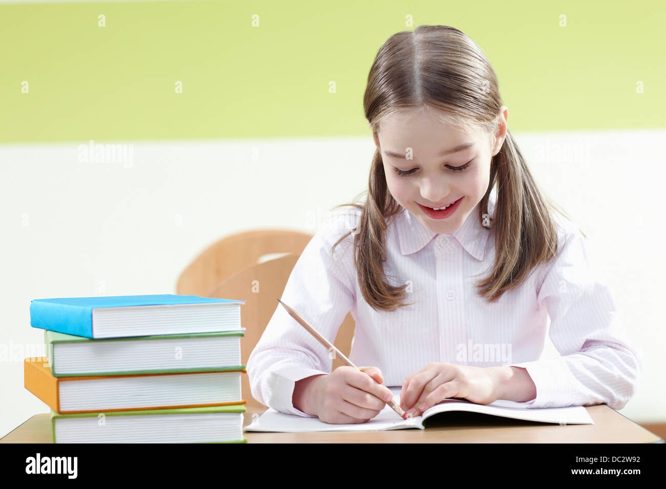 a girl sitting at a desk in a classroom studying Stock Photo - Alamy