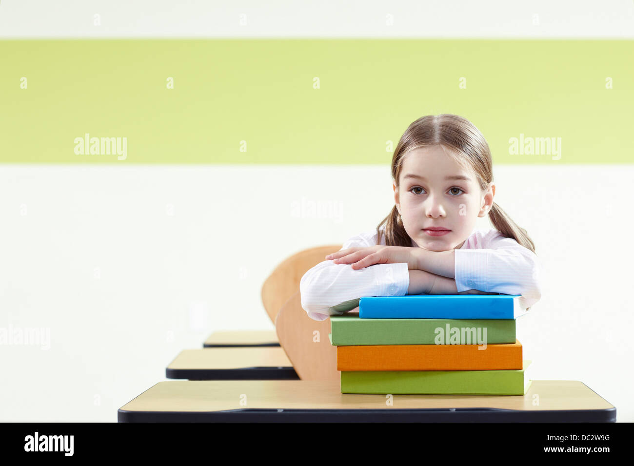 a girl sitting at a desk in a classroom studying Stock Photo - Alamy